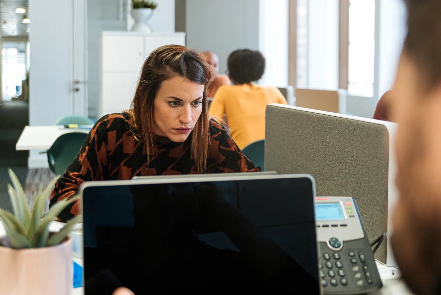A focused professional working at a desk in a modern office, reviewing information and staying organized