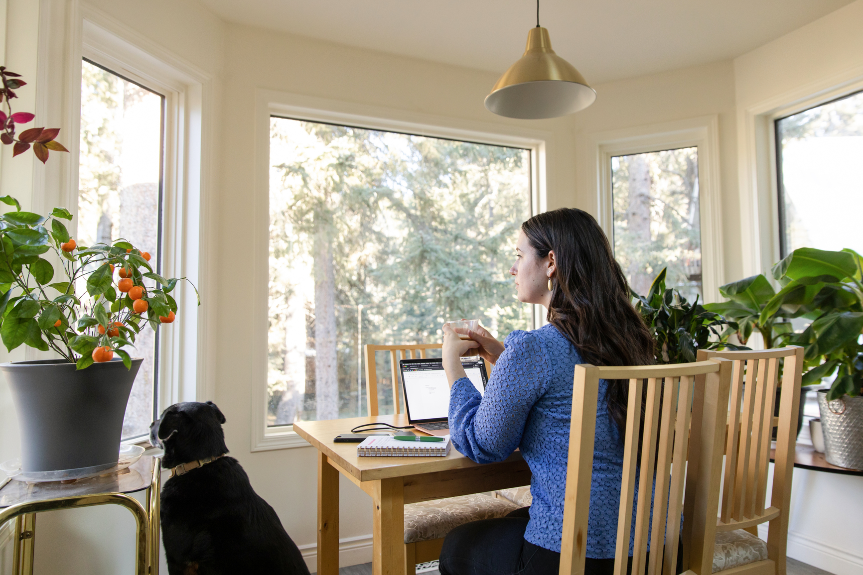 A person working thoughtfully at a table with a laptop and notes, reflecting a calm, focused environment.
